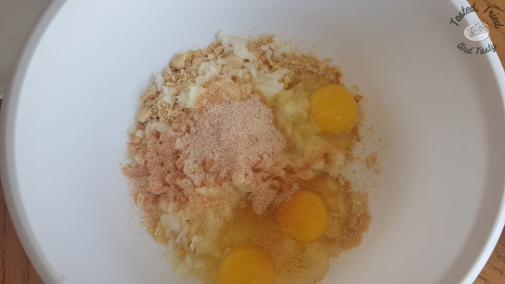 Chopped onion, ritz crackers, seasoning salt, and eggs in a white bowl.