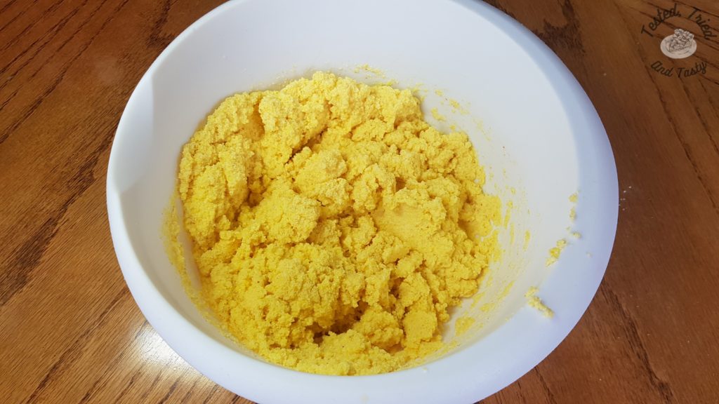 yellow cornmeal soaking in buttermilk in a white bowl.