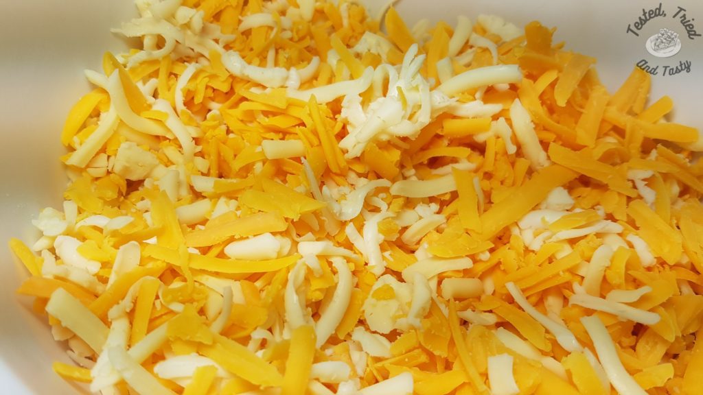 grated sharp cheddar and mozzarella cheeses in a white bowl.