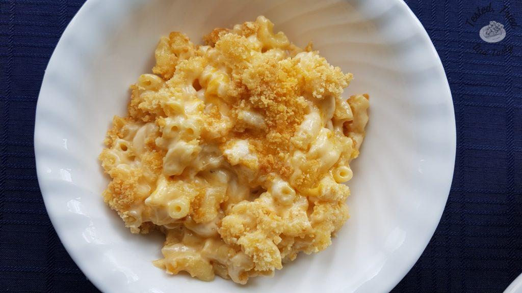 Creamy Baked macaroni and cheese in a white bowl on a blue tablecloth.