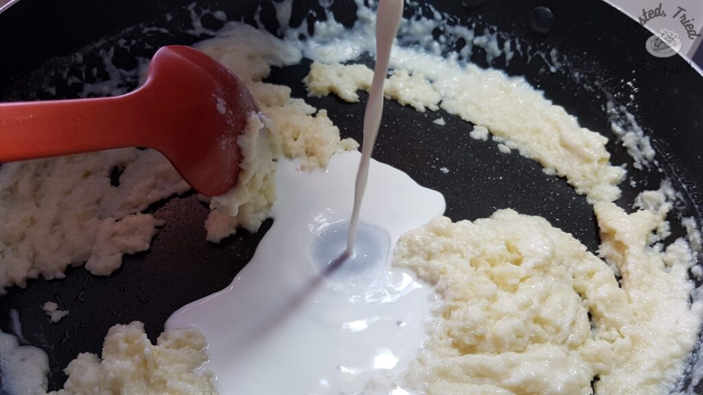 Adding the cream and milk to the flour butter mixture in a large saucepan.