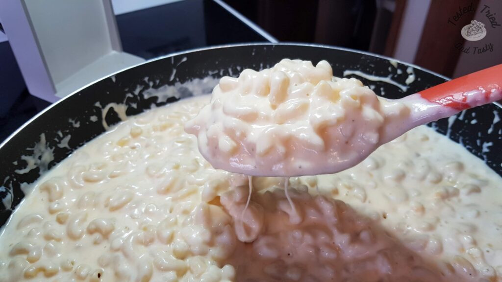 Pasta and cheese sauce in a large saucepan, ready for baked mac and cheese.