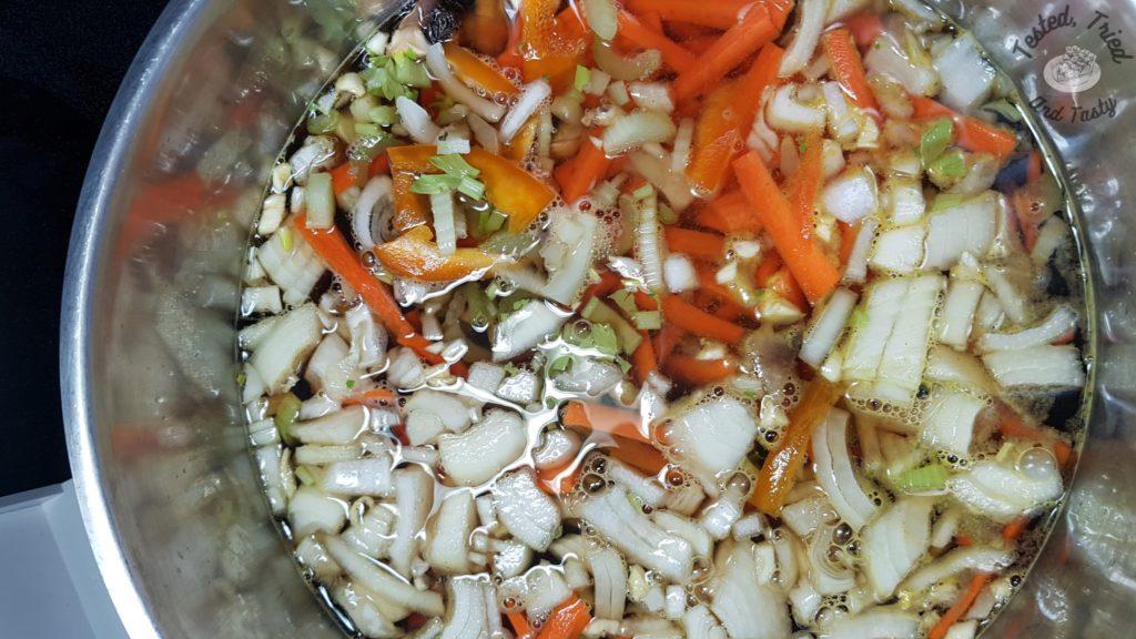 Onions, garlic, carrots and celery in soup broth for homemade soup recipe.