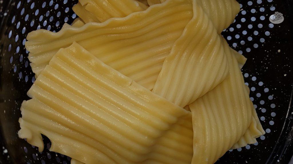 Lasagna noodles in a black strainer.