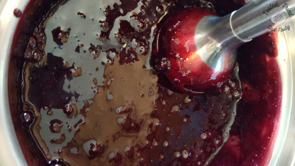 immersion blender in blueberry syrup in a small saucepan