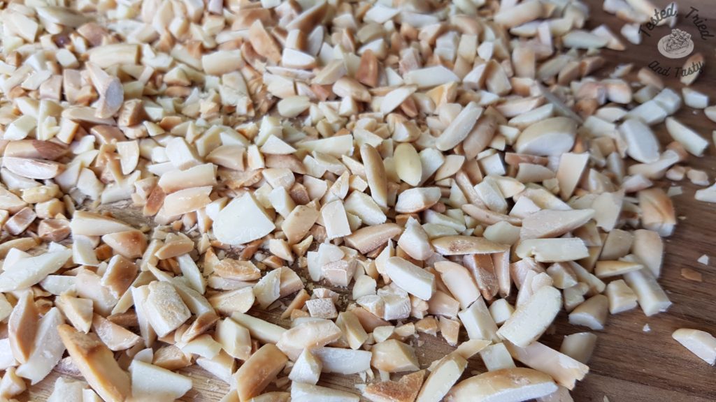 Toasted almonds chopped on a wooden cutting board.