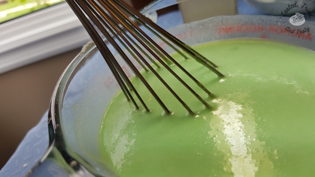 PIstachio pudding being mixed in a glass measuring cup.