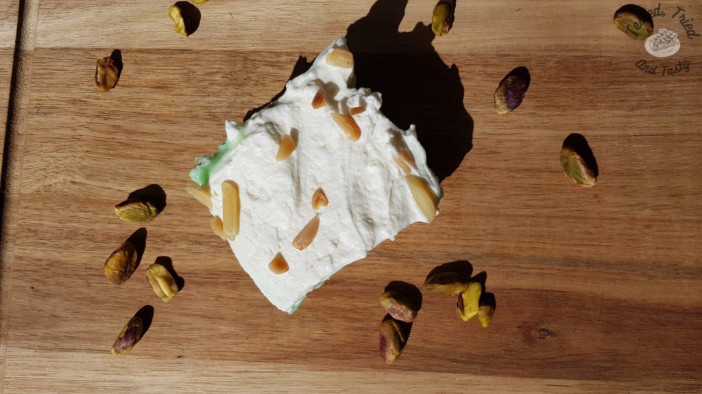 PIstachio pudding dessert on a wooden cutting board with pistachios.