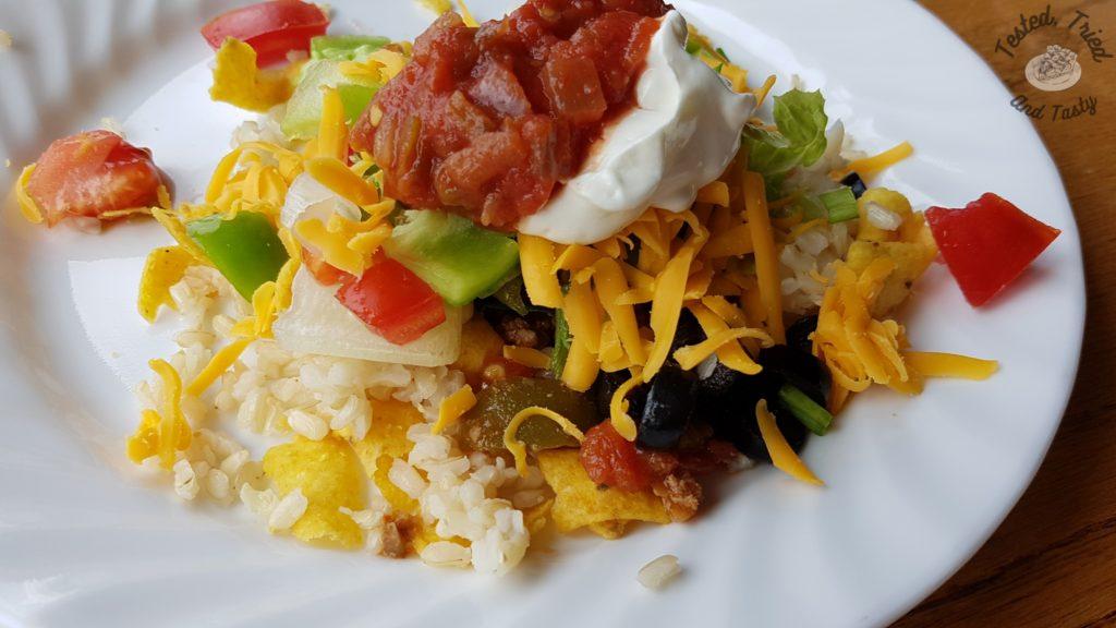 Chili stacker aka haystack on a white plate on a wooden table.