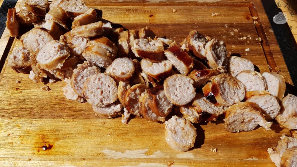 Sliced garlic sausage on a wooden cutting board.