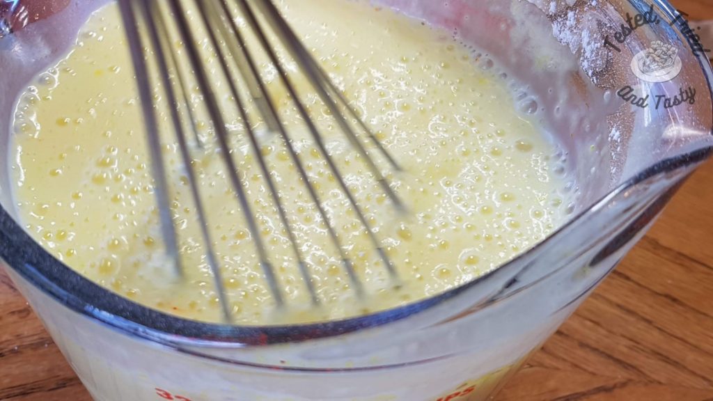 Lemon pudding being mixed in a glass measuring cup.