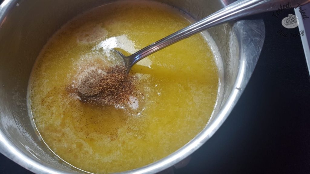 Adding spices to melted butter in a small saucepan.