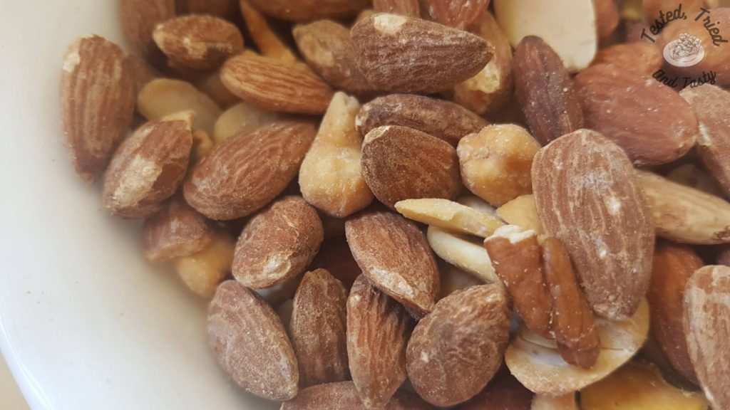 Mixed salted nuts in a white bowl.