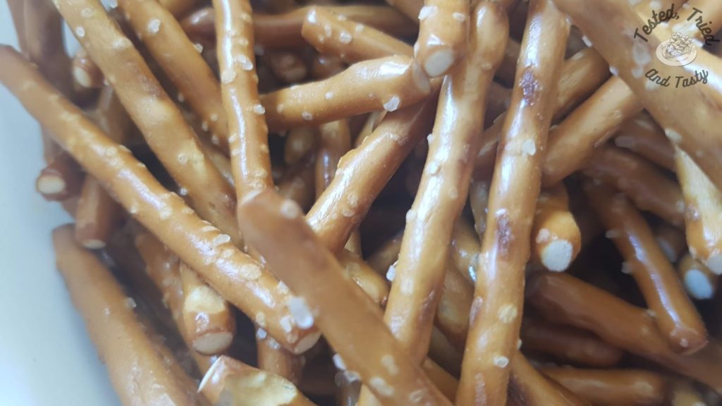 Pretzel sticks in a white bowl.