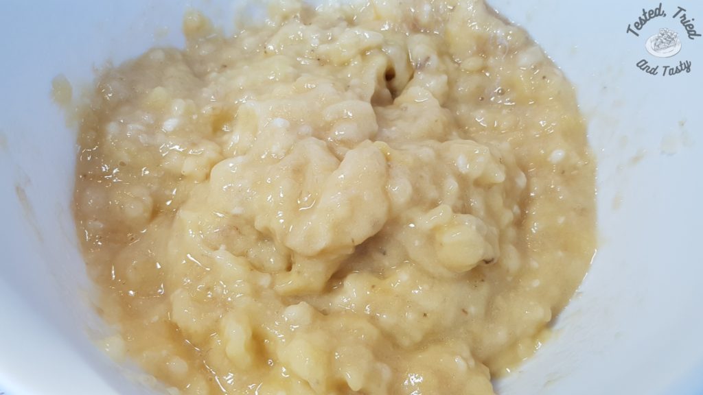 Ripe bananas mashed in a white bowl.