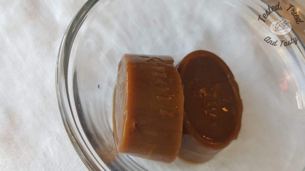 Beef bouillon in a glass bowl on a white tablecloth.