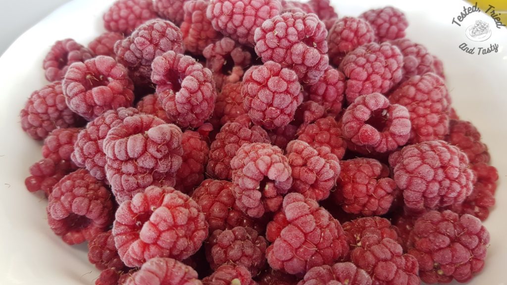 Frozen raspberries in a white bowl.