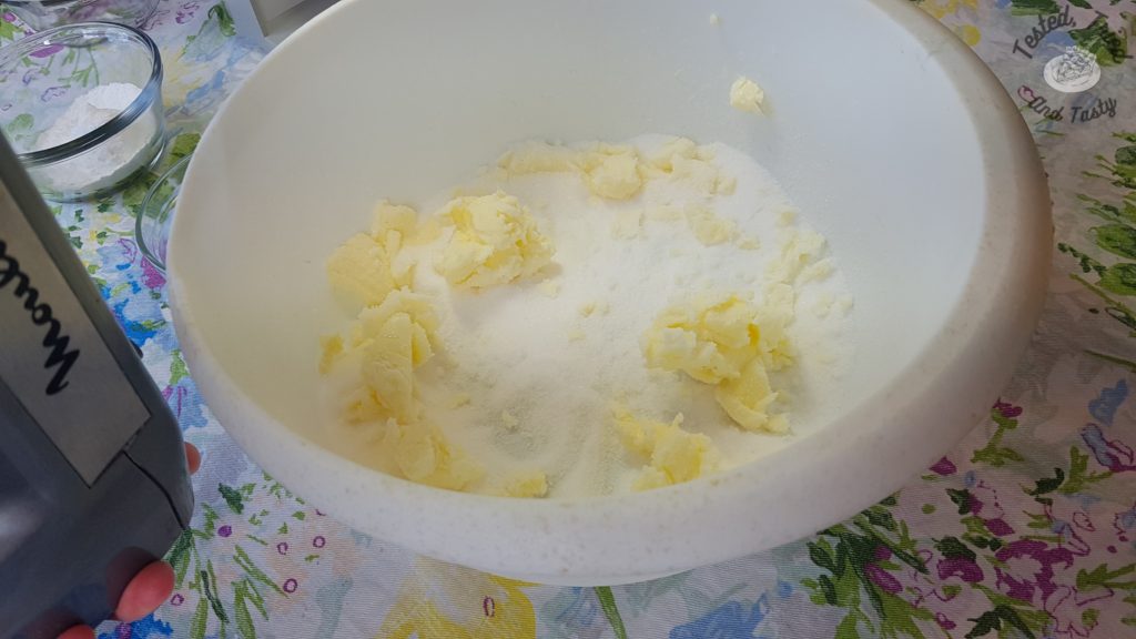 Sugar and butter being creamed together in a white plastic bowl.