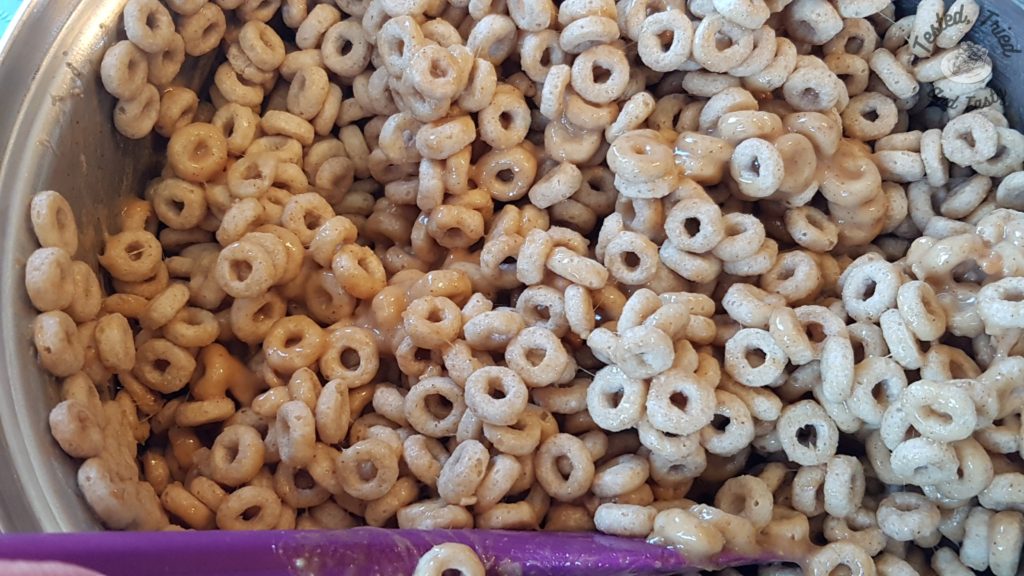 Mixing the honey nut cheerios in with the melted ingredients.