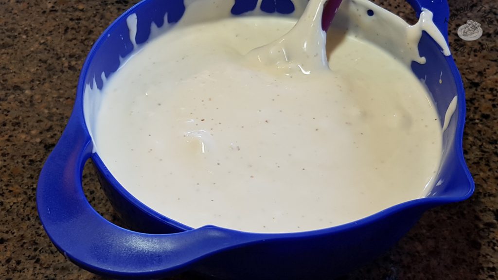 Creamy dressing for dill pickle pasta salad in a blue bowl.