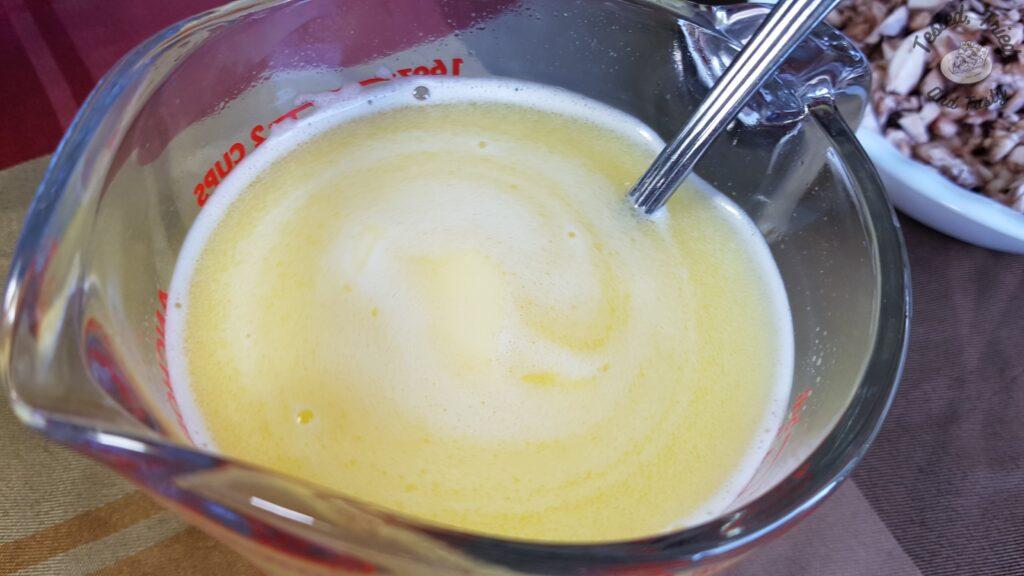 Hot water, butter and chicken bouillon in a glass measuring cup.