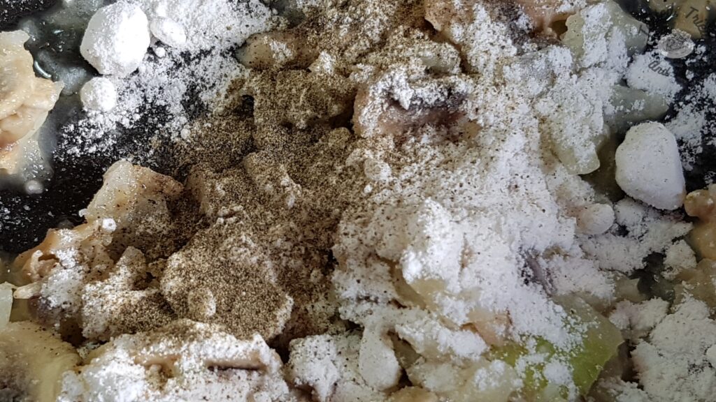 Flour salt and pepper being added to the sauteed mushrooms and onions.