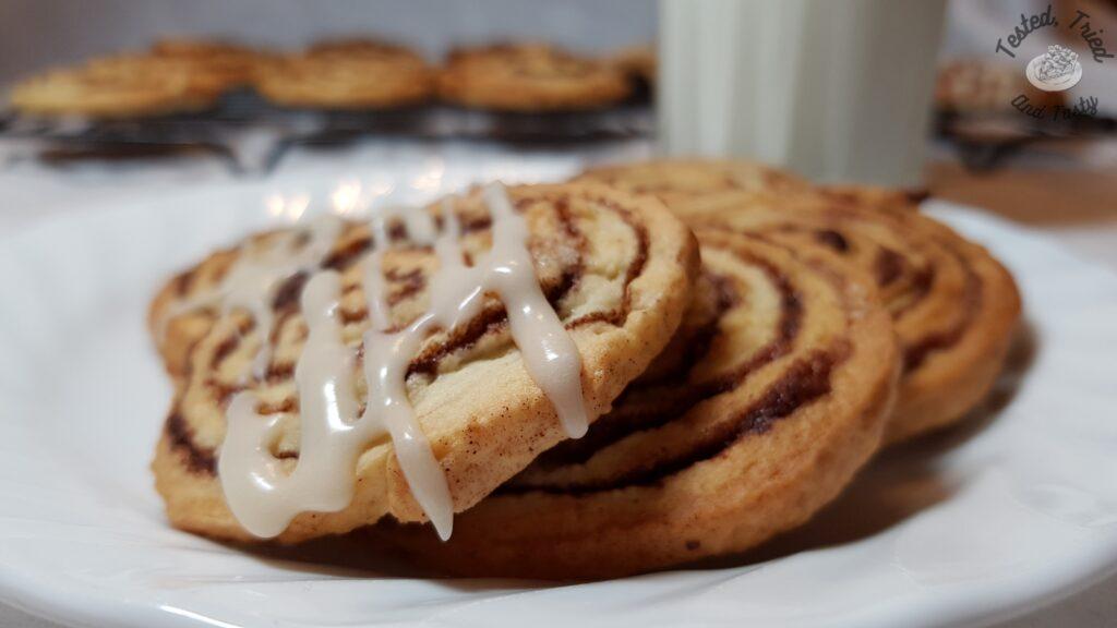 Cinnamon roll cookies on a plate with a glass of milk.