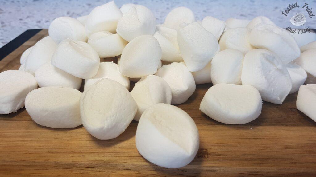 Cut up marshmallows on a wooden cutting board.