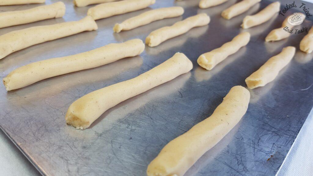 Egg nog cookies shaped into small logs on a baking sheet.