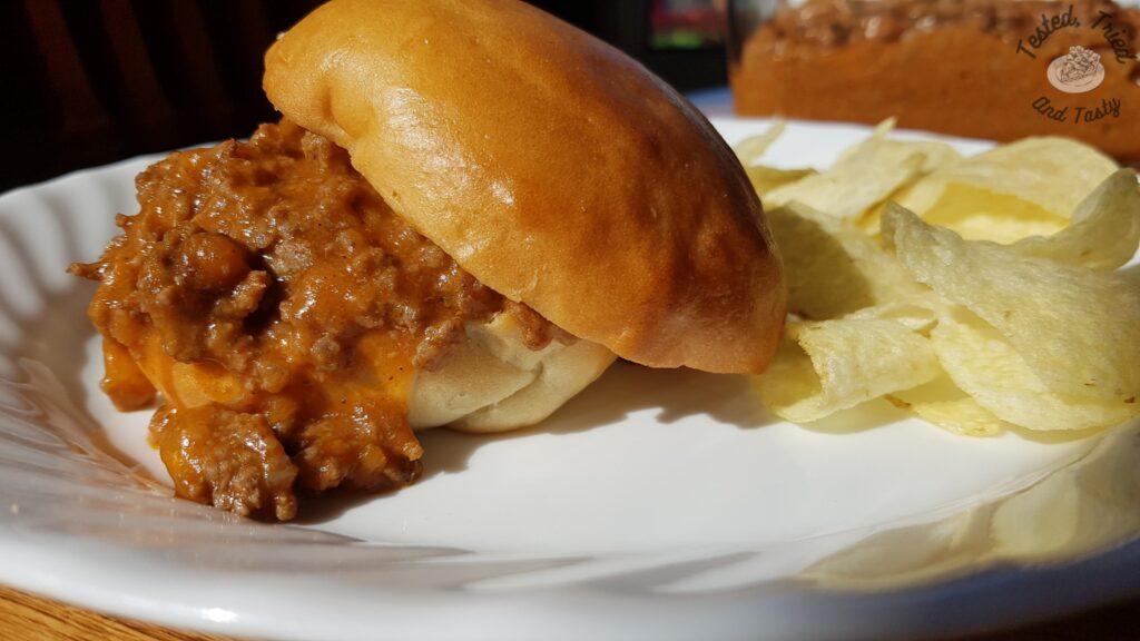 Sloppy Joes recipe on a bun with chips on the side.