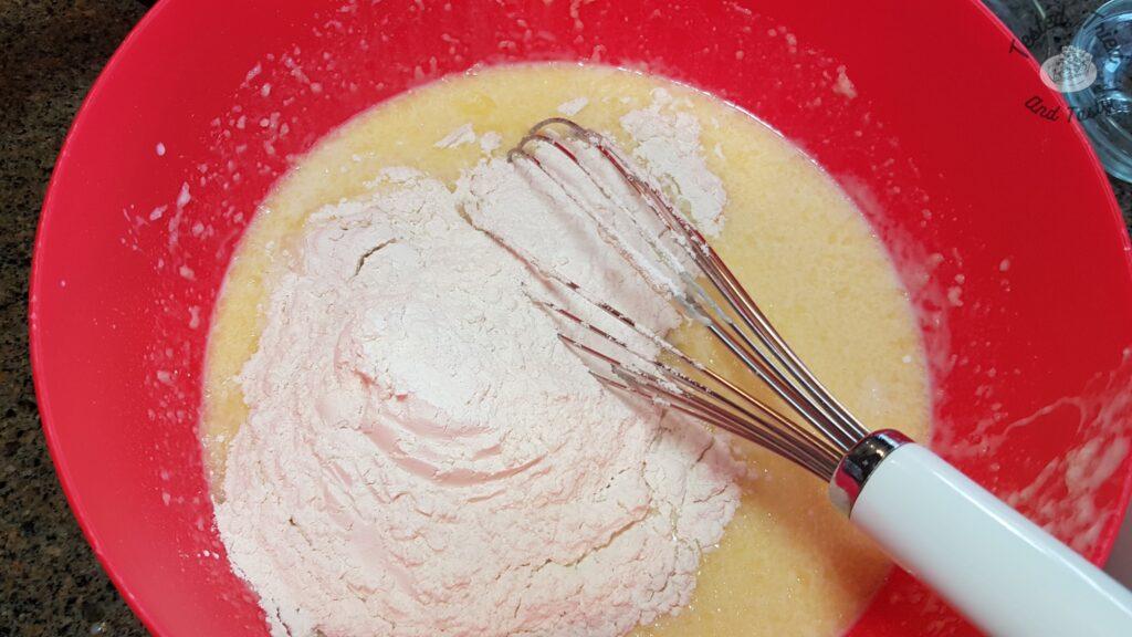 Adding flour to the liquid ingredients.