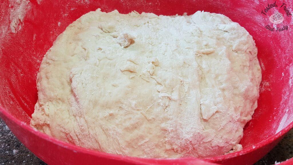 The bread dough roughly mixed in a red bowl.