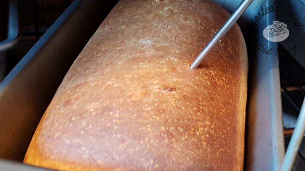 Checking the temperature of a finished sourdough bread loaf.