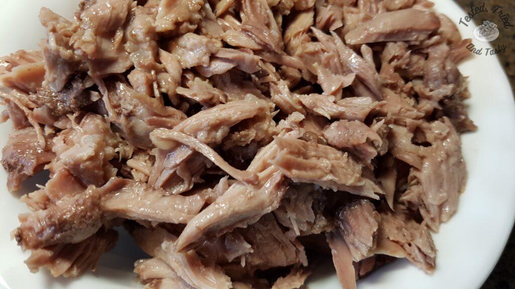 Shredded pork meat in a white bowl.