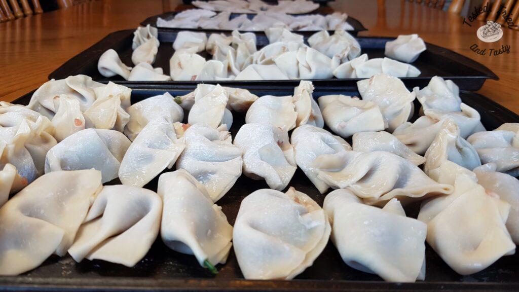 Homemade wontons on baking sheets ready to be frozen.