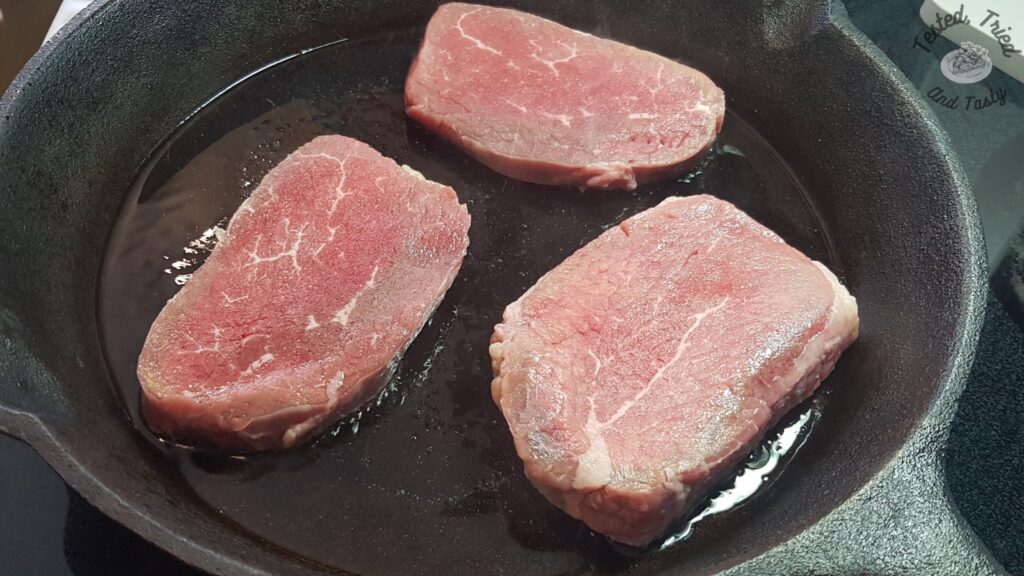 Beef browning in a cast iron pan.