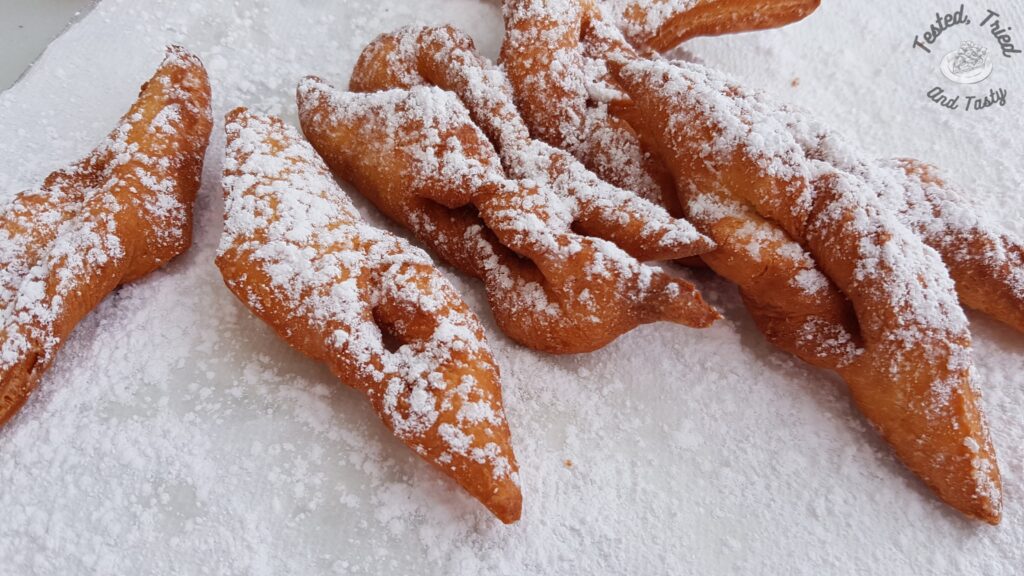 Fattigman cookies finished frying and sprinkled with icing sugar.