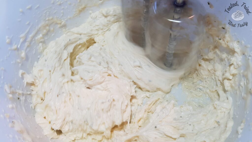 Softened cream cheese being beat in a small bowl.