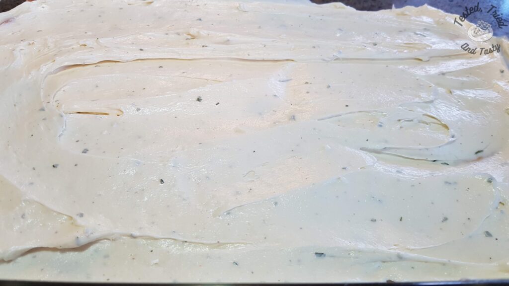 Cream cheese dip spread being spread on pillsbury crescent crust.