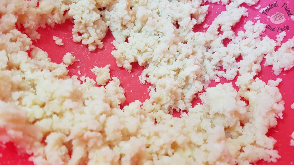 Butter and sugar creamed in a red plastic bowl.