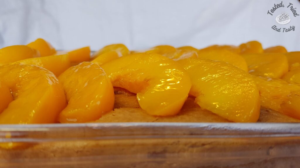 Peach slices placed on the partially baked vanilla cake.