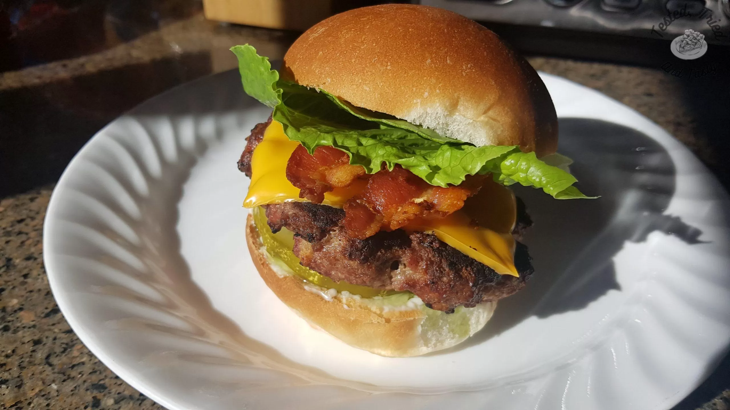 Flavorful homemade hamburgers with cheese, bacon, lettuce on a homemade bun.