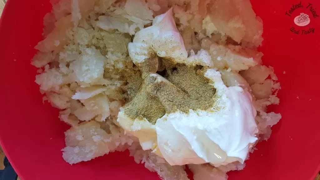 Potatoes with butter and sour cream in a red bowl.