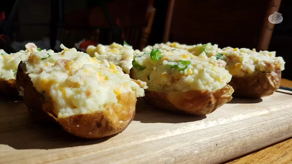 Fully loaded stuffed potatoes on a wood cutting board.
