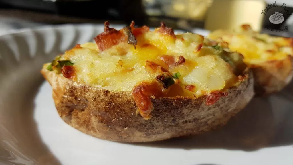 Fully loaded stuffed potato on a white plate.