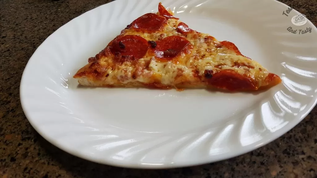 homemade pepperoni and bacon pizza on white plate on counter