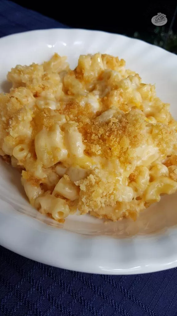 creamy baked macaroni and cheese on a white plate on a blue tablecloth.