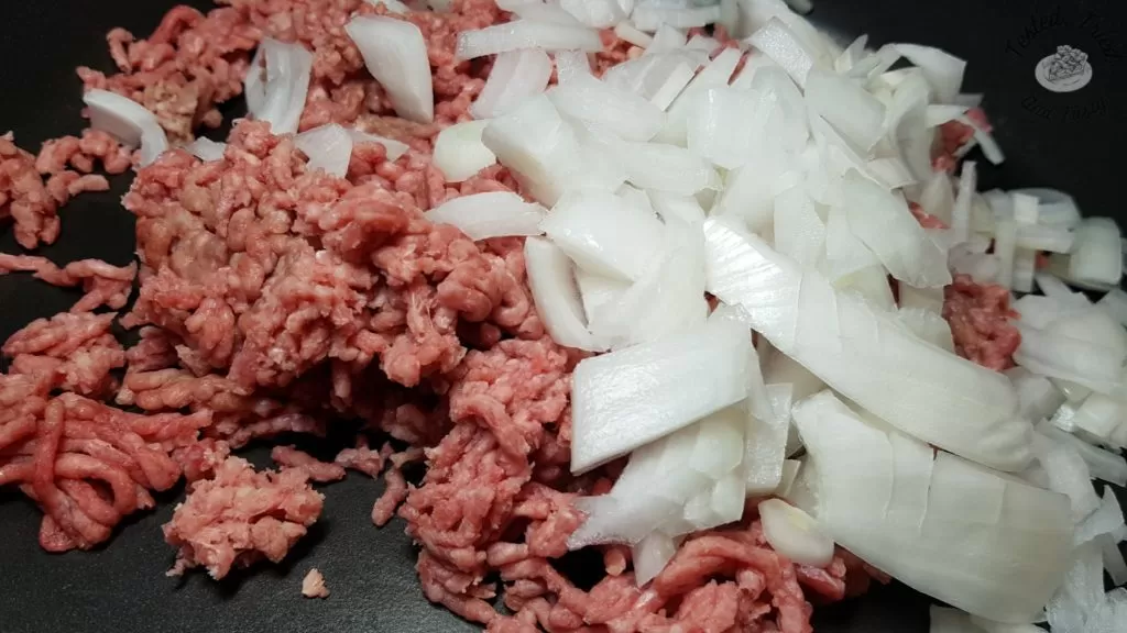 Ground beef with chopped onions in large saucepan.