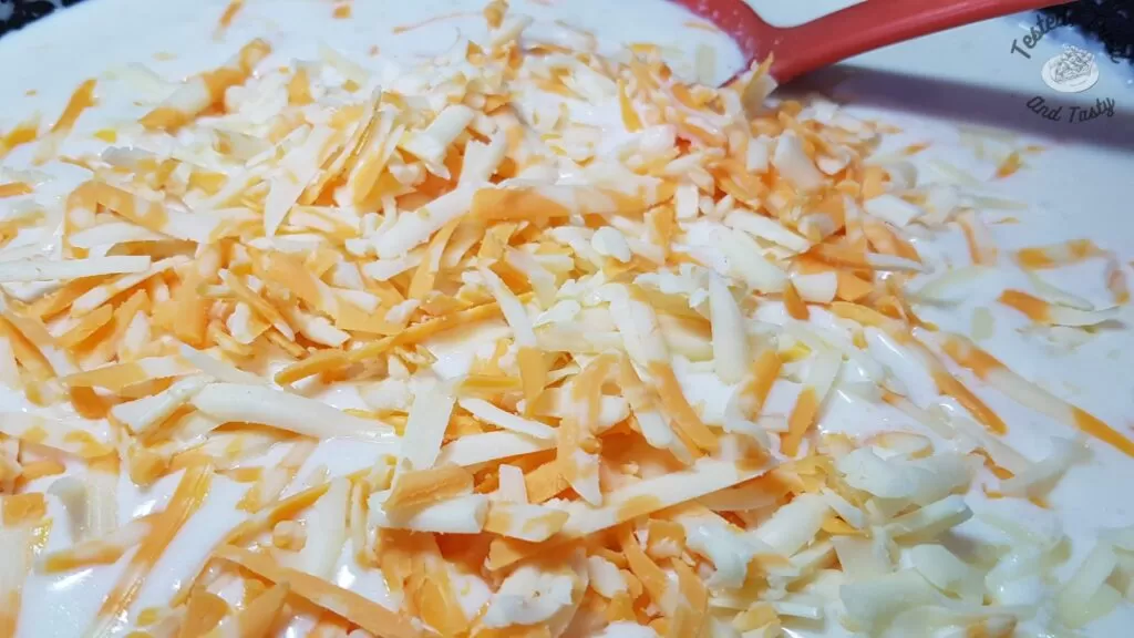 Cheddar cheese added to the thickened milk to make cheese sauce for Macaroni and cheese recipe.