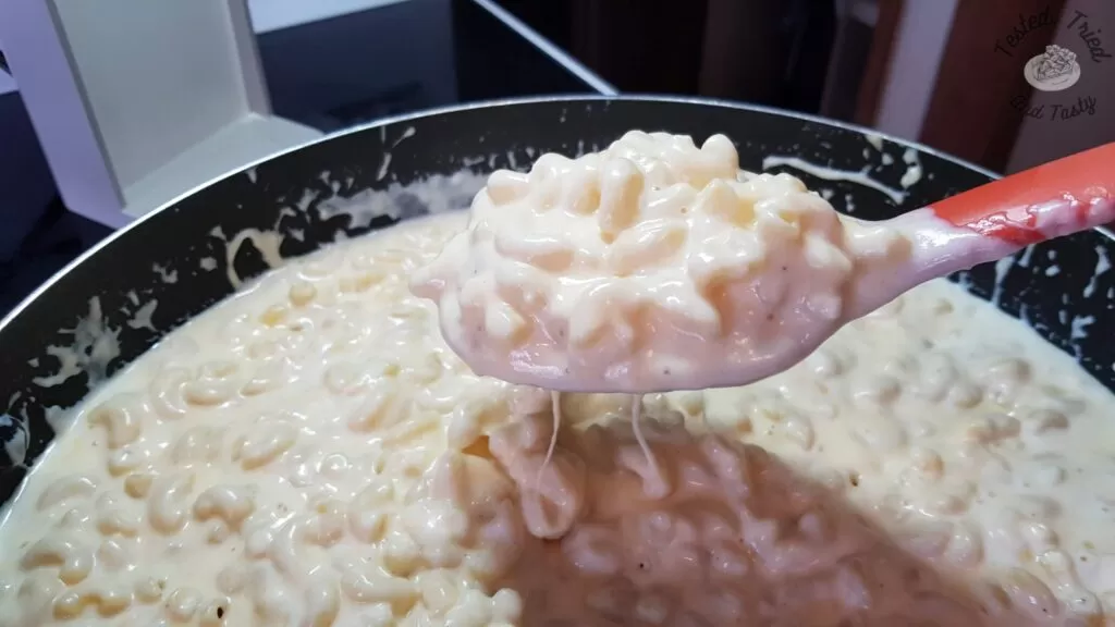 Pasta and cheese sauce in a large saucepan, ready for baked mac and cheese.